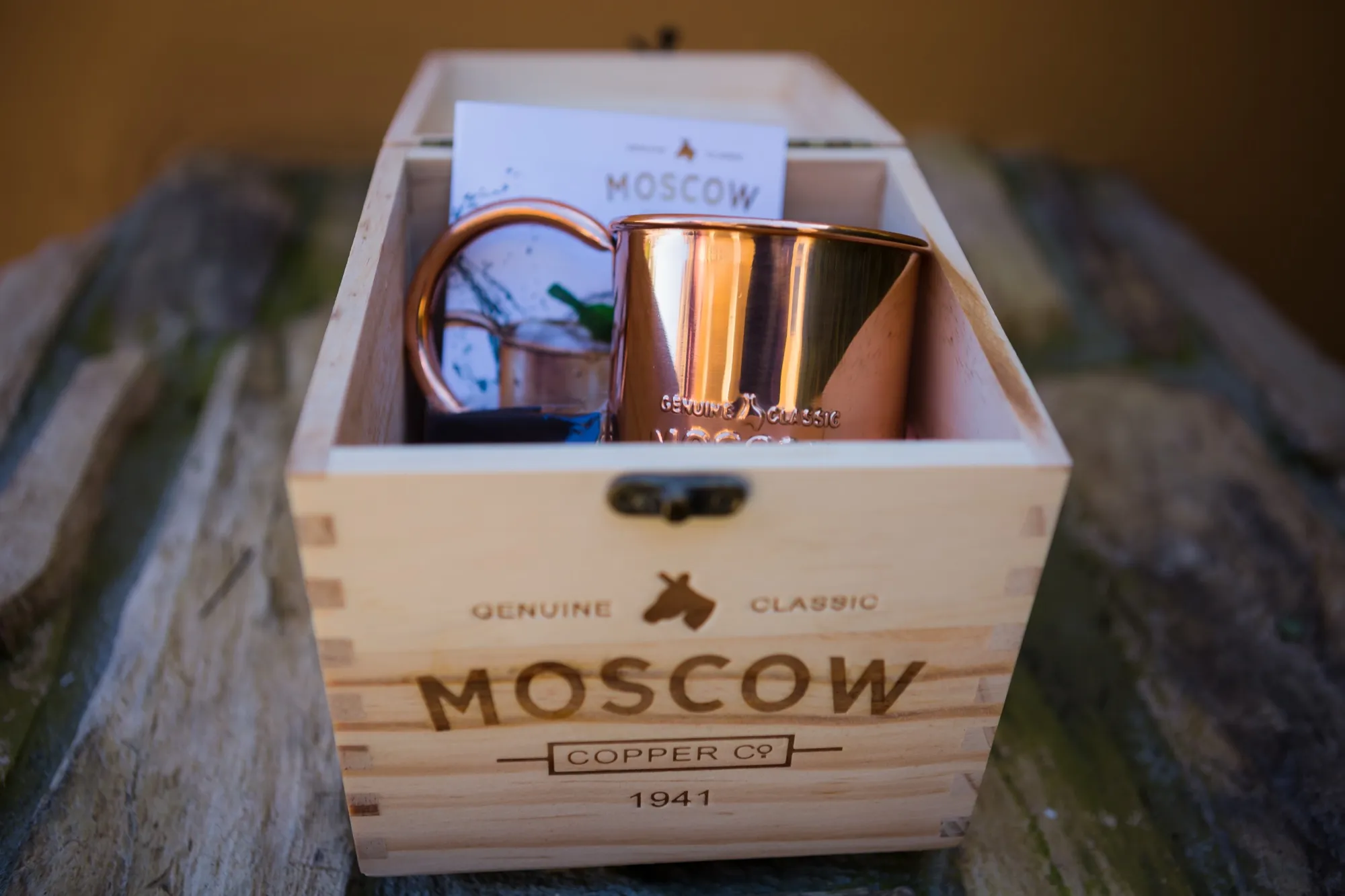 An open branded pine gift crate holding two copper mugs and a recipe card, fire-branded “Genuine Classic Moscow Copper Co. 1941”.