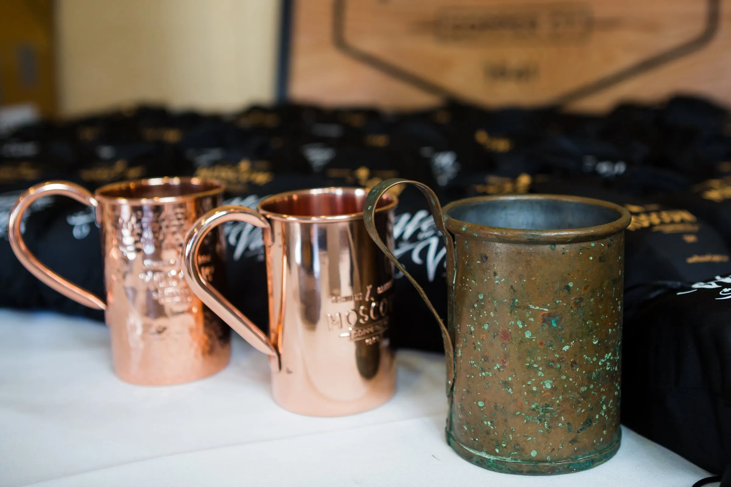 The oxidised original copper mug standing beside two later Moscow Copper Co. production mugs on a table.