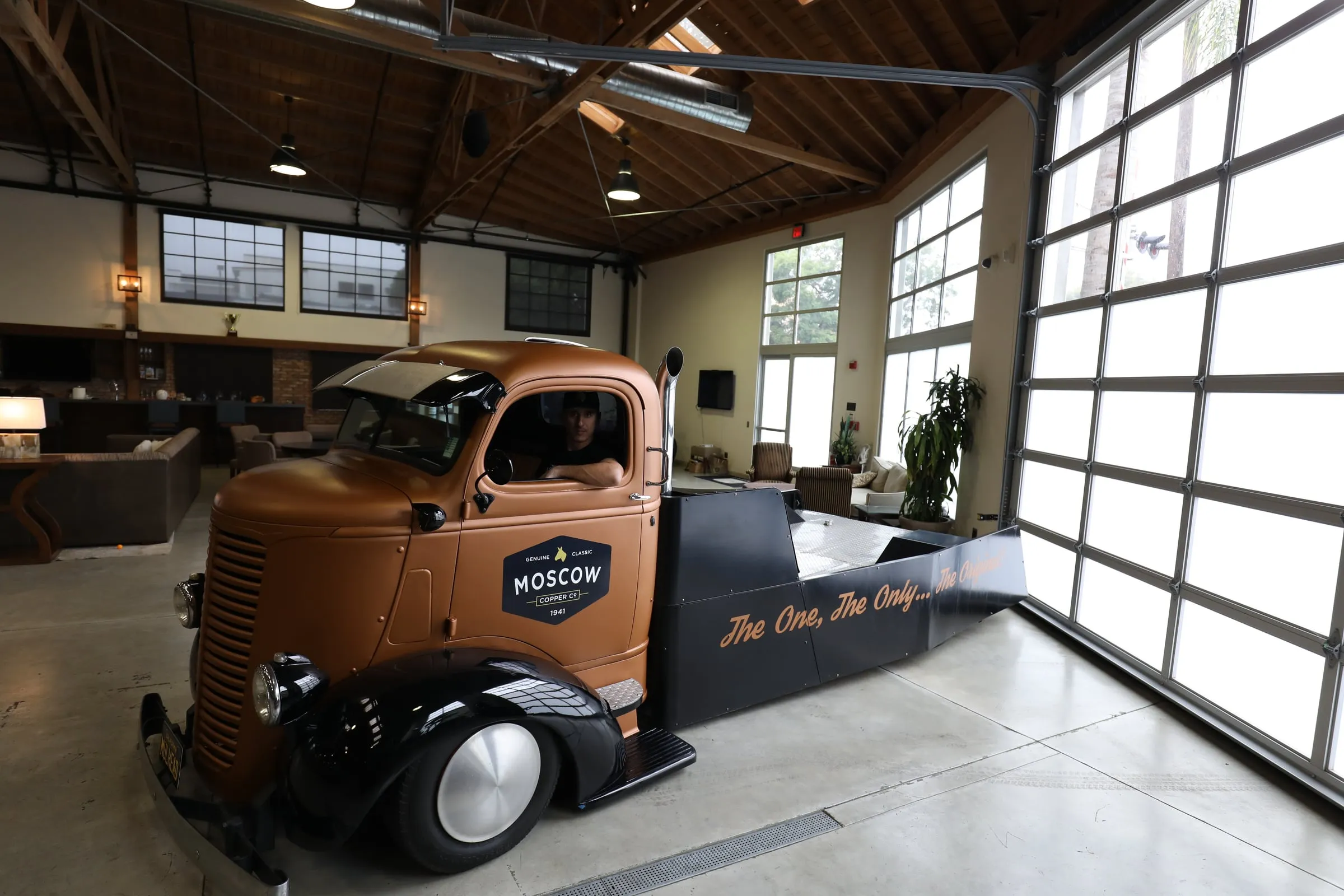 The Moscow Copper Co. 1939 cab-over truck in copper livery inside the showroom, lettered “The One, The Only… The Original!”, with the front wheel, cab and rear bed in full view.