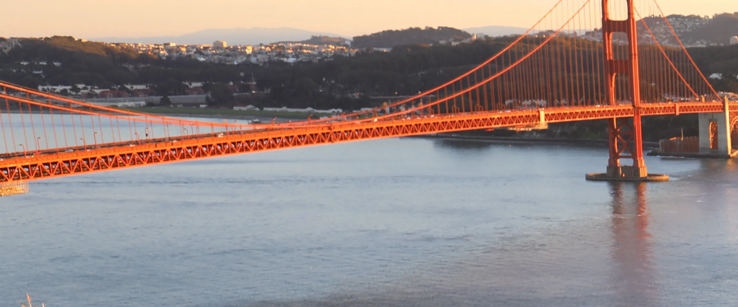 The Golden Gate Bridge seen from the Marin Headlands, a tower and the span above the water.